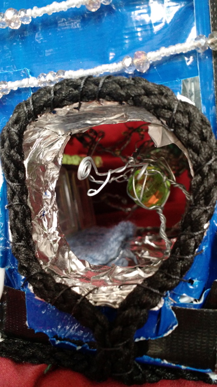 Close-up of the rope-ringed doorway from outside, focusing on the creature about to leave through it. One spiral tentacle is reaching straight out through the opening.